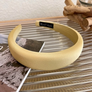 Detailed view of glossy yellow satin padded headband showing fine fabric texture on glass
