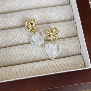 Detail of vintage heart glass earrings with gold rose pins in a jewelry box