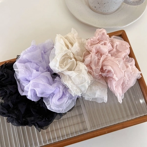 Detail of mesh scrunchies in pastel colors on a glass tray with elegant pleats