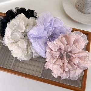 Set of four pastel organza scrunchies in black, cream, purple, and pink on wooden tray