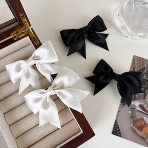 Detail von vier schwarz-weißen Satin-Haarschleifen in einer eleganten Lifestyle-Szene