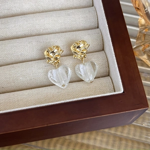 Detail of vintage French gold rose earrings with translucent glass heart pendants