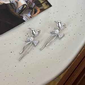 Detail of silver heart bow earrings with long tassels and sparkling zircon stones