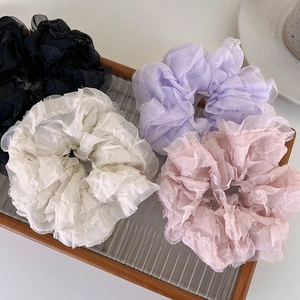 Detail view of four pleated mesh scrunchies in black, white, purple and pink colors