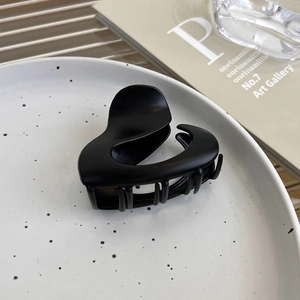 Dettaglio della piccola molletta per capelli a cuore nero opaco su un piatto di ceramica