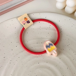 Détail d'un chouchou rouge élastique avec breloque de glace rose et étiquette fleurie