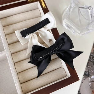 Makroansicht von seidigen Satin-Haarspangen in Creme und Schwarz auf einer Schmuckbox