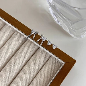 Detail view of heart-shaped zircon earrings set on a beige velvet jewelry display tray