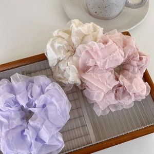 Three oversized organza scrunchies in purple, beige and pink displayed on a glass tray