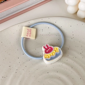 Détail d'un élastique à cheveux bleu clair avec breloque lapin gâteau et étiquette