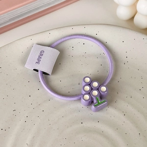 Détail d'un élastique à cheveux violet avec pendentif raisin en résine et étiquette