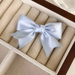 Detailansicht der eleganten hellblauen Satin-Schleife Haarklammer auf einer Schmuckschatulle