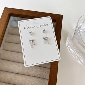 Detailed set of silver heart zircon earrings and waterdrop pendants on a white jewelry card