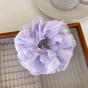 Detail of light purple organza scrunchie with pleated mesh texture on a wooden tray
