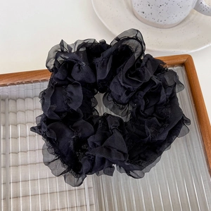 Detail of elegant black mesh oversized scrunchie with pleated ruffles on a glass tray