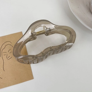 Détail d'une pince à cheveux nuage marron translucide avec ressort en métal doré