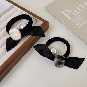 Détail de deux chouchous à nœuds en satin avec perles et breloques en acétate