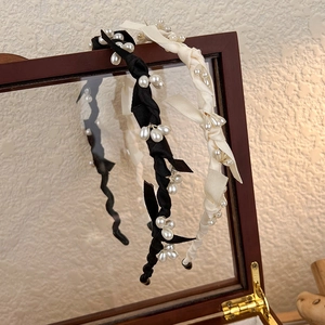 Détail de serre-têtes élégants à perles en noir et crème sur cadre en bois vintage