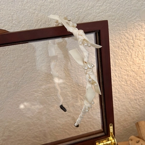 Détail du serre-tête en satin blanc avec perles nacrées et décoration de nœud
