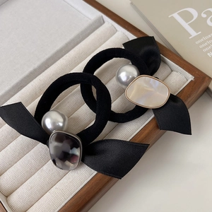 Détail de chouchous nœuds noirs avec perles et pierres dans un plateau à bijoux en bois