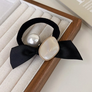 Détail d'un chouchou à nœud noir avec perle blanche et ornement en résine crème chic