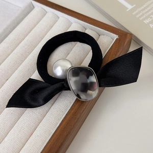 Détail du chouchou nœud noir avec perle blanche et breloque en acrylique marbré