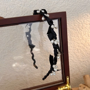 Détail d'un bandeau élégant en tissu noir orné de perles d'imitation blanches chic
