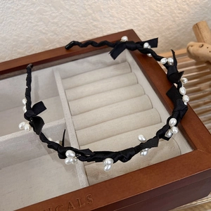 Détail d'un serre-tête noir élégant avec perles et nœuds sur un coffret en bois