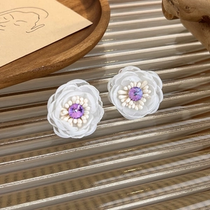 Elegant white mesh flower earrings with purple crystal center on textured glass base