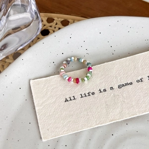 Macro shot of colorful beaded elastic ring with silver cube beads on vintage paper
