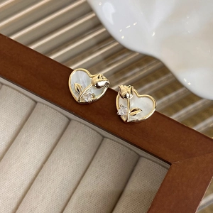Detalle de pendientes de corazón dorados con tulipán de nácar y piedra de circón brillante