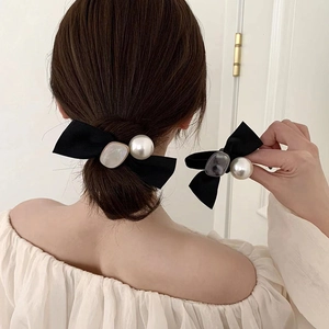 Chouchou noeud noir élégant avec perle et détail en acétate présenté sur un chignon