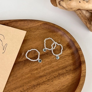Three beaded S925 silver rings with blue crystal charms on a rustic wooden tray