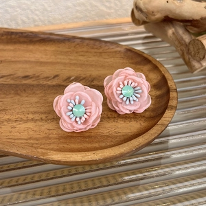 Detail of sweet mesh flower earrings featuring green crystal center and blue beaded stamens