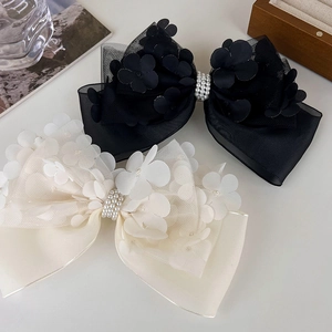 Détail de barrettes noeud en dentelle mesh avec fleurs 3D et perles pour un style chic
