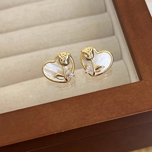 Detalle de pendientes de corazón en nácar con tulipa dorada y pequeña piedra de circón