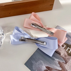 Detail von rosa und lila Satin-Schleifen-Haarspangen mit Perlen und Entenschnabelclip