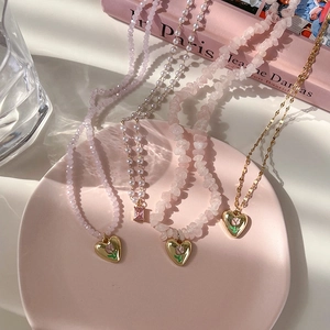 Détail du pendentif tulipe cœur avec colliers superposés en cristal rose et perles