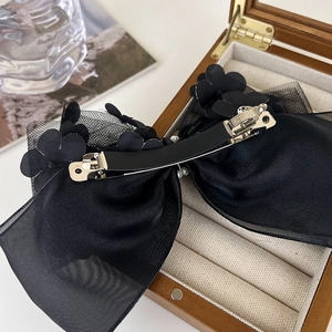 Détail de la pince à cheveux noeud en organza noir avec fleurs et pince métallique