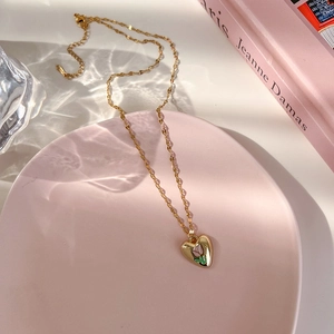Détail d'un pendentif cœur avec tulipe rose sur une chaîne dorée et fermoir mousqueton