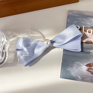 Detail einer hellblauen Satin-Schleifen-Haarklammer mit zentraler Perlenverzierung