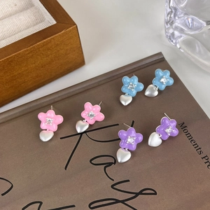 Trois paires de boucles d'oreilles fleurs et cœurs colorées avec zircon sur livre