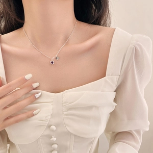 Dettaglio della collana con pendente a cuore in argento e zircone viola su una modella