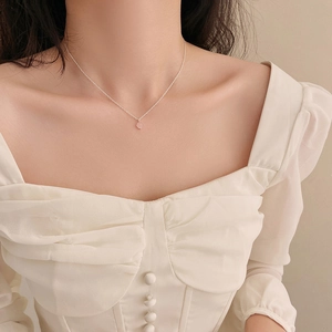Détail d'un collier minimaliste en argent avec pendentif cristal rose clair porté