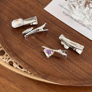 Set di fermagli per capelli argentati con strass iridescenti su vassoio in legno