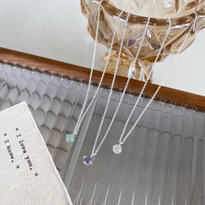 Vue détaillée de pendentifs ronds en cristal vert, violet et blanc sur des chaînes en argent