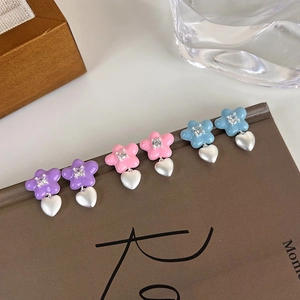 Détail de trois paires de boucles d'oreilles fleur et cœur colorées avec zircons sertis