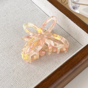 Detailed close-up of a hollow butterfly hair claw made of pink and yellow acetate resin