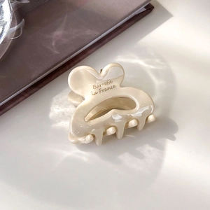 Vue détaillée d'une mini pince à cheveux crème avec l'inscription dorée Barrette La France