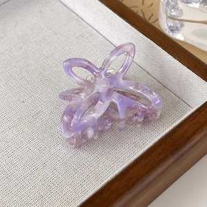 Close-up of a purple marble acetate butterfly hair claw clip on a fabric display tray